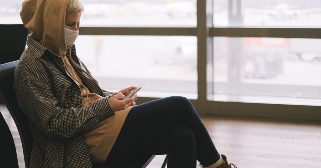 A traveller with a phone beside an airport window