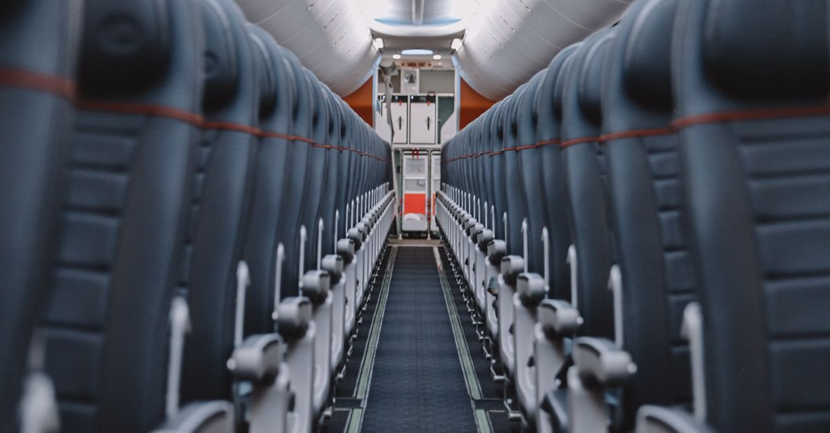 Rows of economy seats along the aisle of a narrow-body airliner cabin