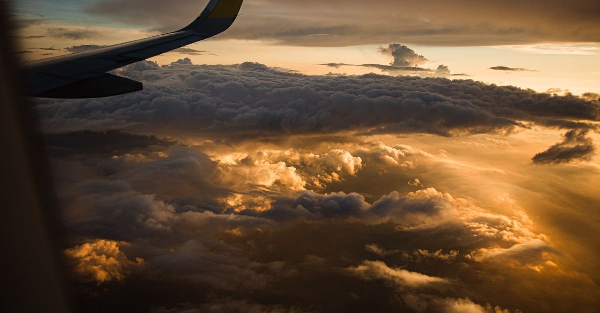 An aircraft wing above clouds at sunset