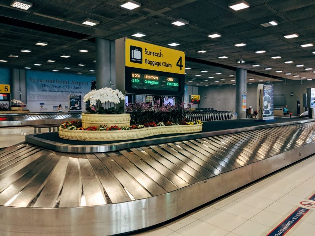 An empty baggage claim carousel in an airport arrivals hall beneath a baggage claim sign
