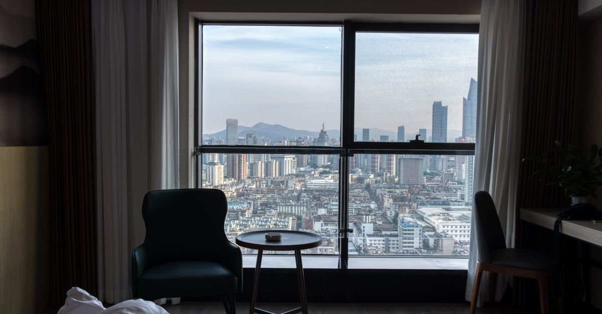 A hotel room with a city view through the window